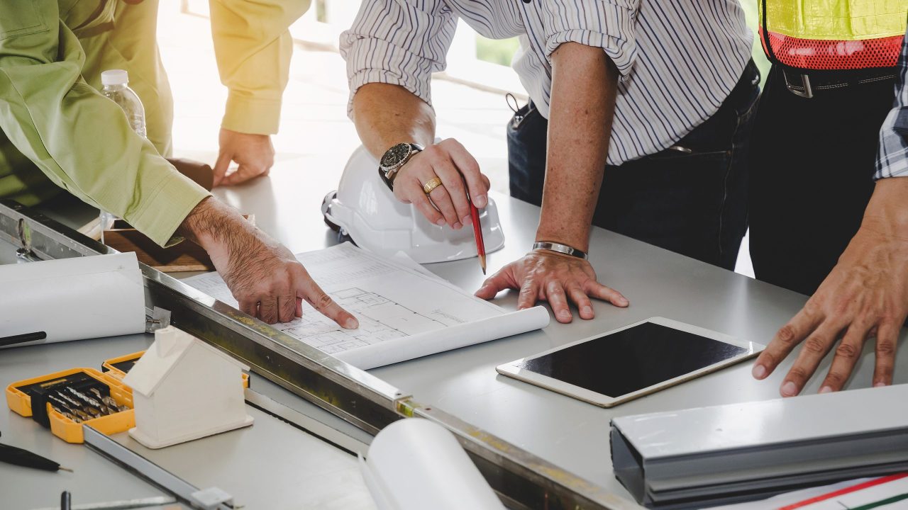 Construction Worker Team Planning About Building Plan With Bluep construction worker team planning about building plan with blueprint, safety helmet, construction tools on conference table at construction site, contractor, business, industry, construction concept